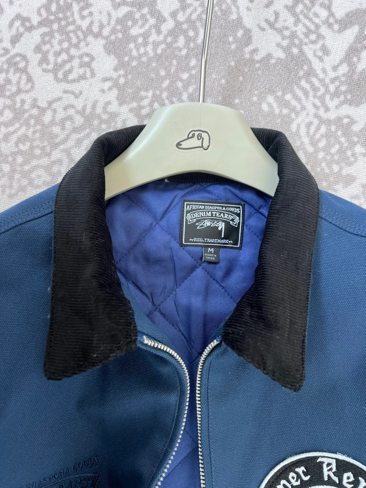 New T66# jacket version 340💰/quilted version 360💰 Stussy x Denim Tears joint model SS25 round chest logo printed zipper opening work jacket, same style for men and women, navy blue Accessories: original dismantling and development, one-to-one customized small labels, collar labels, washing, hang tags, hardware, etc. - Fabric: It is made of the original one-to-one 275g pure cotton fabric, and the high-count double yarn process improves softness and durability. The whole piece is washed, giving it a vintage navy blue distressed texture, echoing the nostalgic tone of the campus theme.   - The collar part is spliced ​​with corduroy or cotton fabrics, which contrasts with the washed cotton of the main body to enhance the visual layering and improve wearing comfort.    - The iconic "Double S + Kapok Ring" combination logo on the back is three-dimensional embroidery. The cotton texture and letter lines stand out in three-dimensionality, enhancing brand recognition.   - A small area of ​​embroidery, card colors and Never Renege slogans are added to the side to echo the cultural theme of the African American community.   - Continuing the short and wide cut of the Detroit work jacket, the cuffs and hem are tightened to give both functionality and practicality.   - The interior adopts quilting technology to provide moderate warmth while maintaining lightness, which is suitable for spring when the temperature difference between morning and evening is large.     - Equipped with YKK metal zipper, it opens and closes smoothly and is durable, and the edge wrapping process improves the overall structural strength.  - African cultural elements: symbols such as the Ace of Spades, the Bid Whist card game scene, and the Jamaican high school area code "718" are integrated into the single product through embroidery, printing and other processes to convey the cultural proposition of Denim Tears.  - Joint logo: Stussy double S logo and Denim Tears kapok ring are combined with embroidery and printing to strengthen the uniqueness of the joint series.  Size: M-2XL M bust 127 length 65.5 sleeve length 61 shoulder width 53.3 [160-165cm 60-70kg] L bust 132 length 66.8 sleeve length 62.2 shoulder width 55.9 [165-170cm 70-85kg] 【170-175cm 80-95kg】 XXL Bust 142.2 Clothes Length 69.3 Sleeve Length 64.8 Shoulder Width 61 【175-180cm 90-105kg】